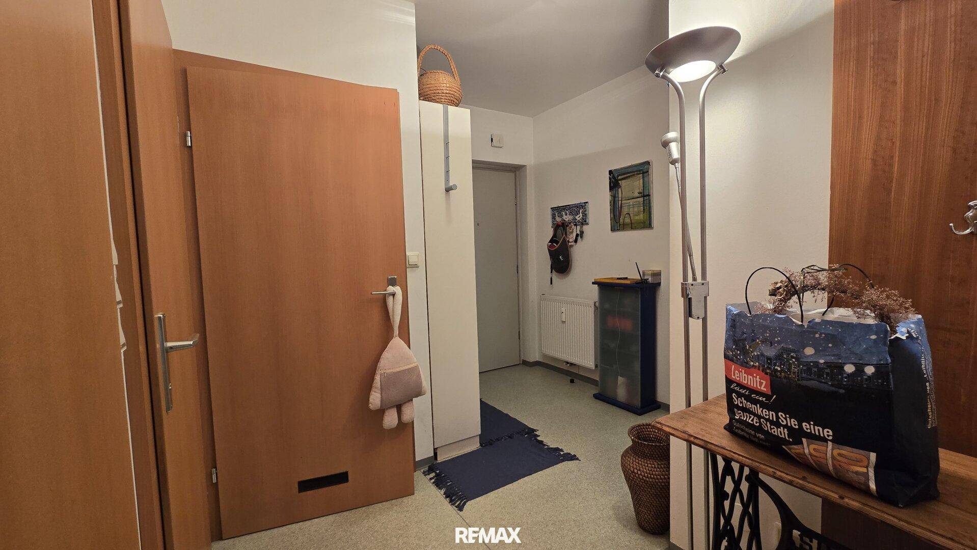 Heller Flur mit Holztüren, Garderobe und Stehlampe, bietet einen freundlichen Empfangsbereich.
