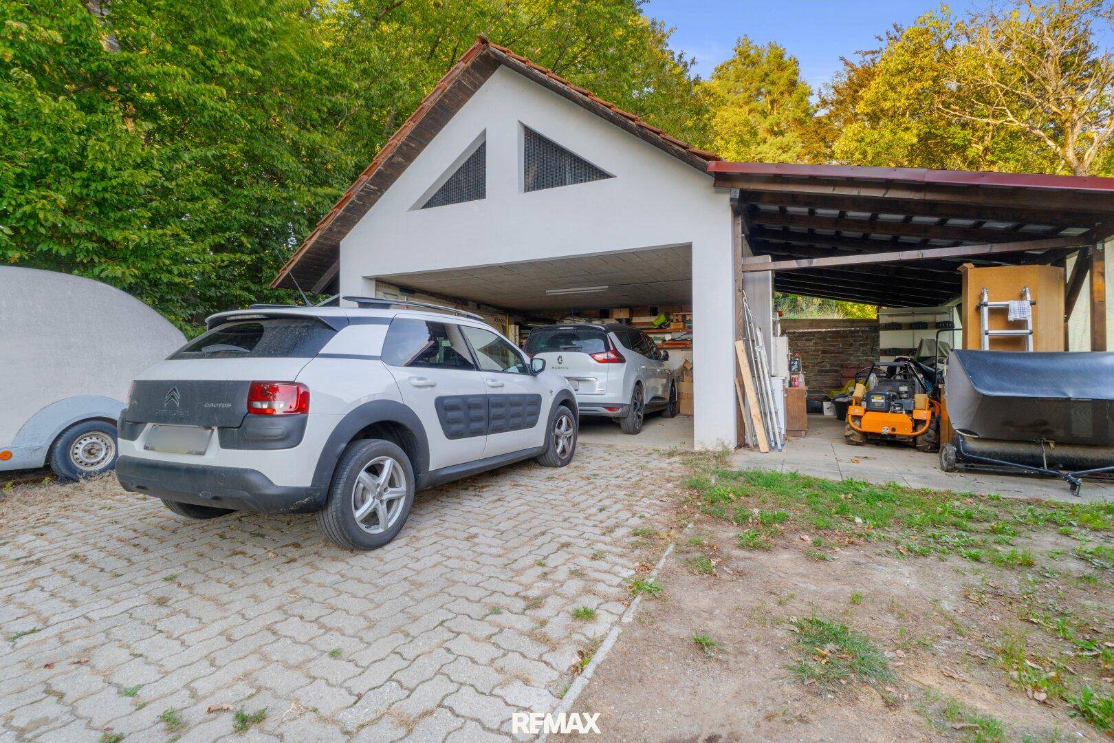 Geräumige Garage mit angrenzendem Carport, bietet Platz für mehrere Fahrzeuge und Lagerung.