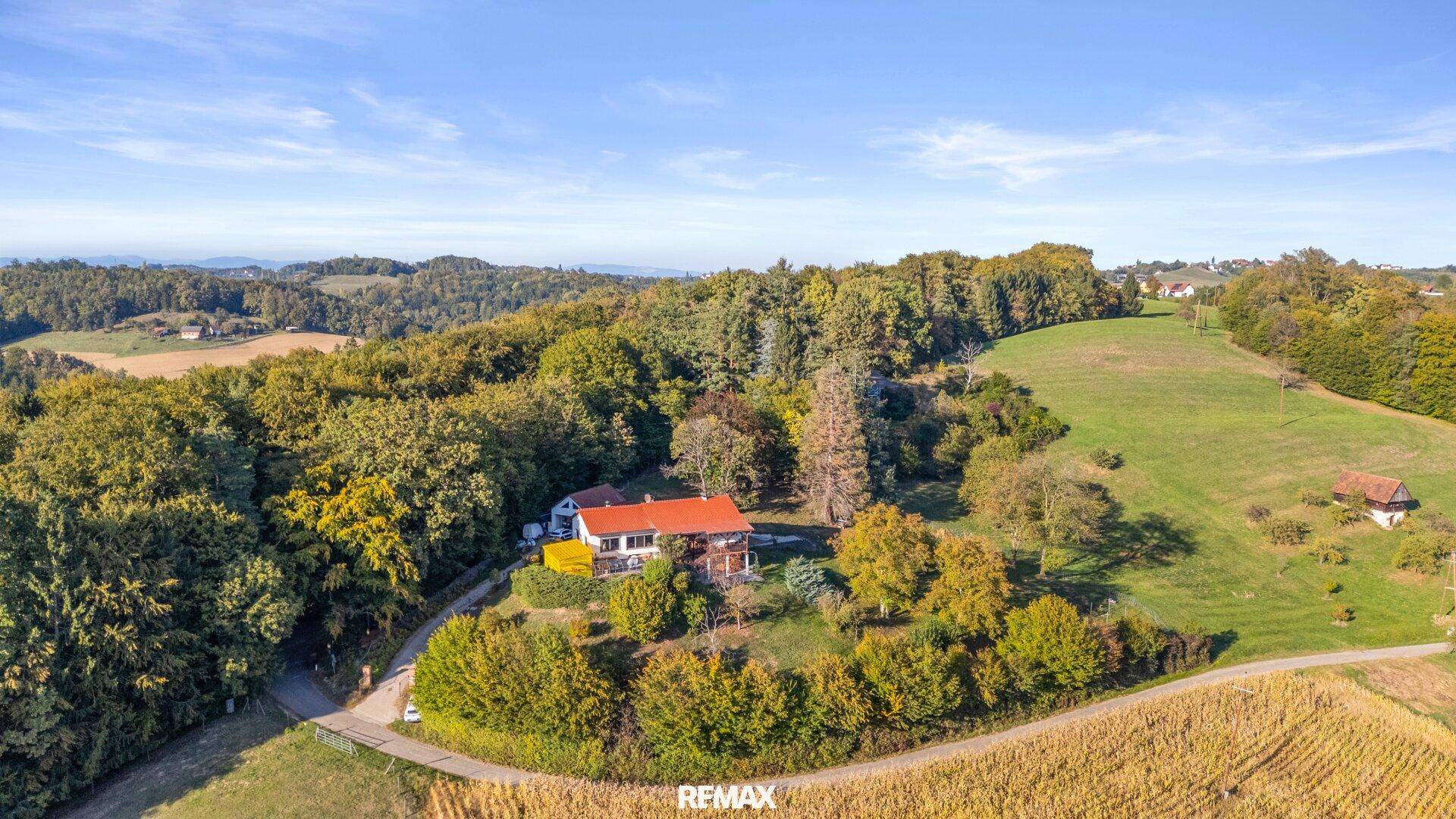 Weitläufige Luftaufnahme des Anwesens, eingebettet in eine hügelige Landschaft mit Feldern und Wäldern.