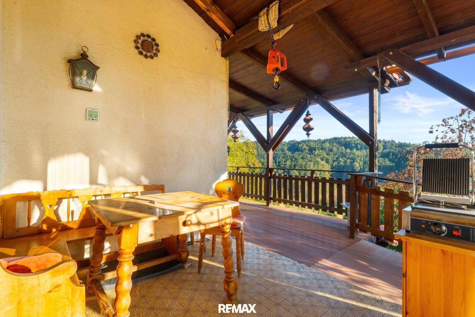 Rustikale überdachte Terrasse mit Holztisch und Bänken, perfekt für gesellige Stunden im Freien.