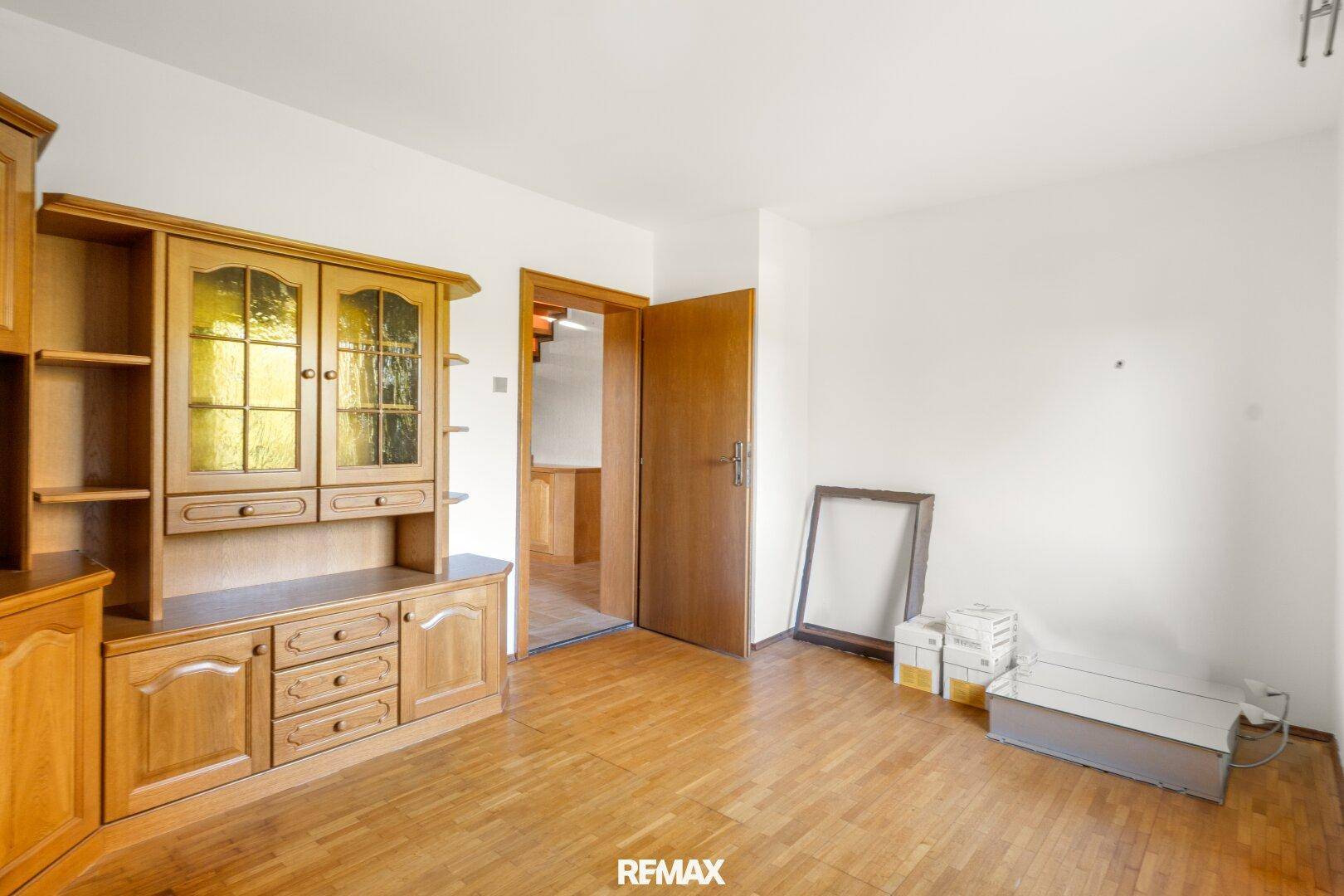 Zimmer mit Holzboden, traditionellem Schrank und Zugang zu einem weiteren Raum.
