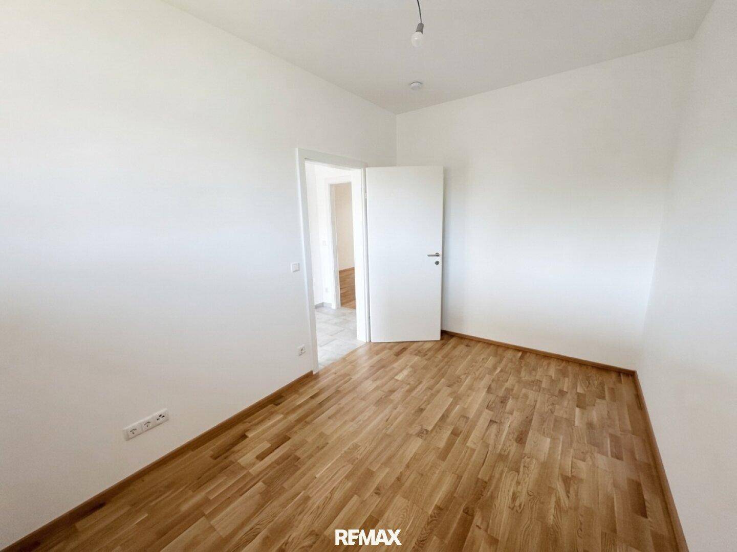Geräumiges, unmöbliertes Zimmer mit Parkettboden und Zugang zu weiteren Räumen.