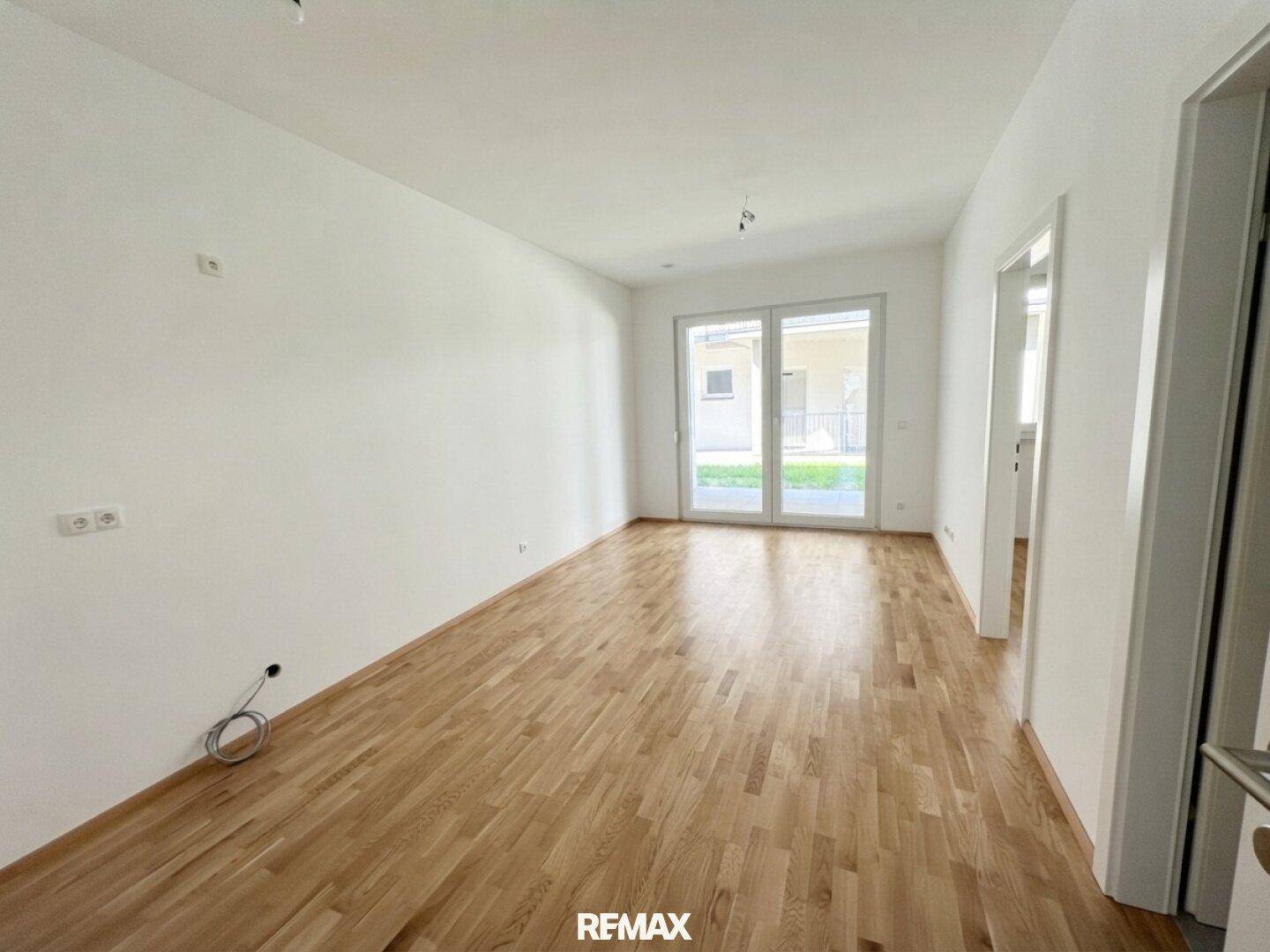 Großes, helles Wohnzimmer mit Holzboden und direktem Zugang zur Terrasse oder zum Garten.