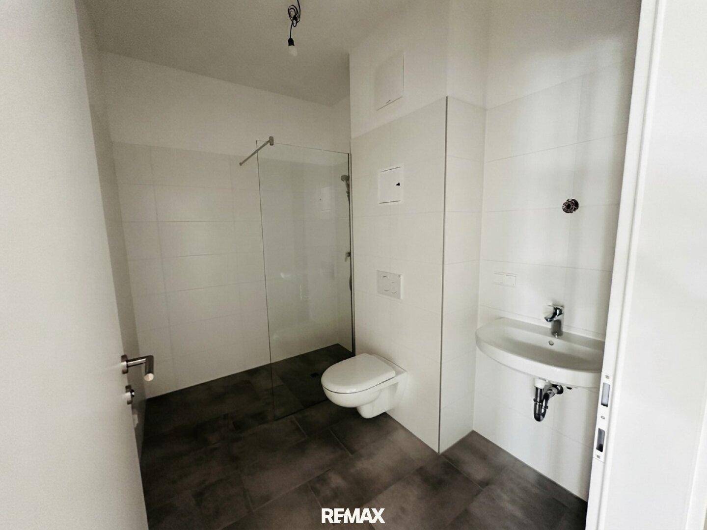Modernes Badezimmer mit begehbarer Dusche, wandhängendem WC und stilvollen Fliesen.
