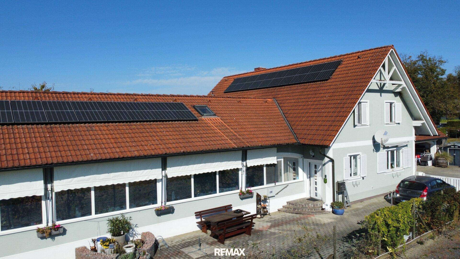 Vogelperspektive des Hauses mit Photovoltaikmodulen auf den roten Ziegeldächern und gepflegtem Außenbereich.