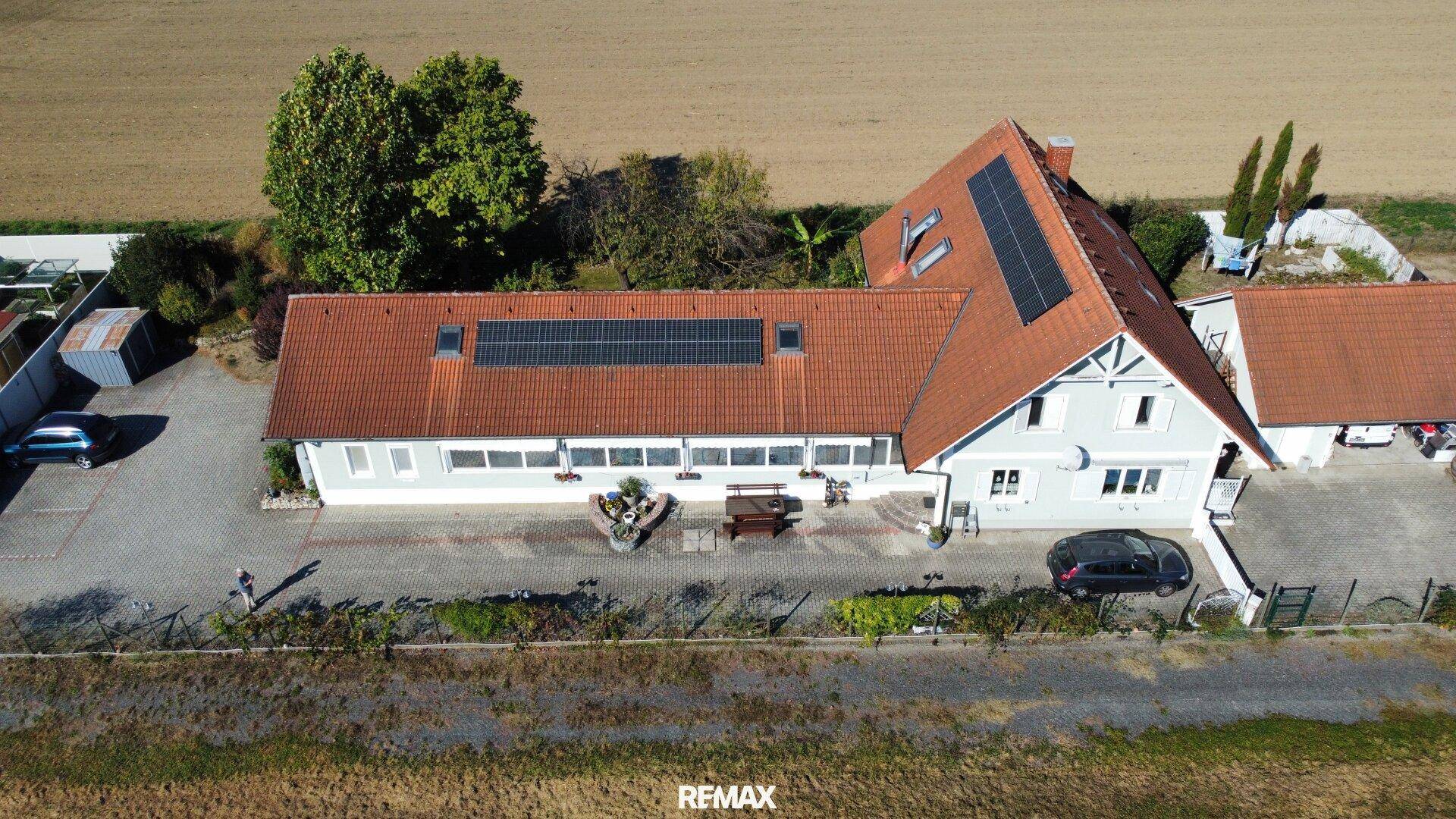Weitläufige Luftaufnahme des Hauses mit Photovoltaik auf dem Dach und ländlicher Umgebung.