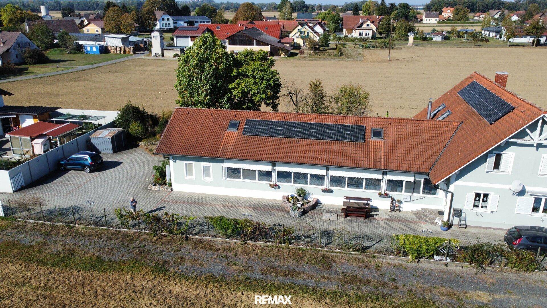 Luftbild des Wohnhauses mit Photovoltaikanlage und angrenzenden Feldern in sonniger Lage.