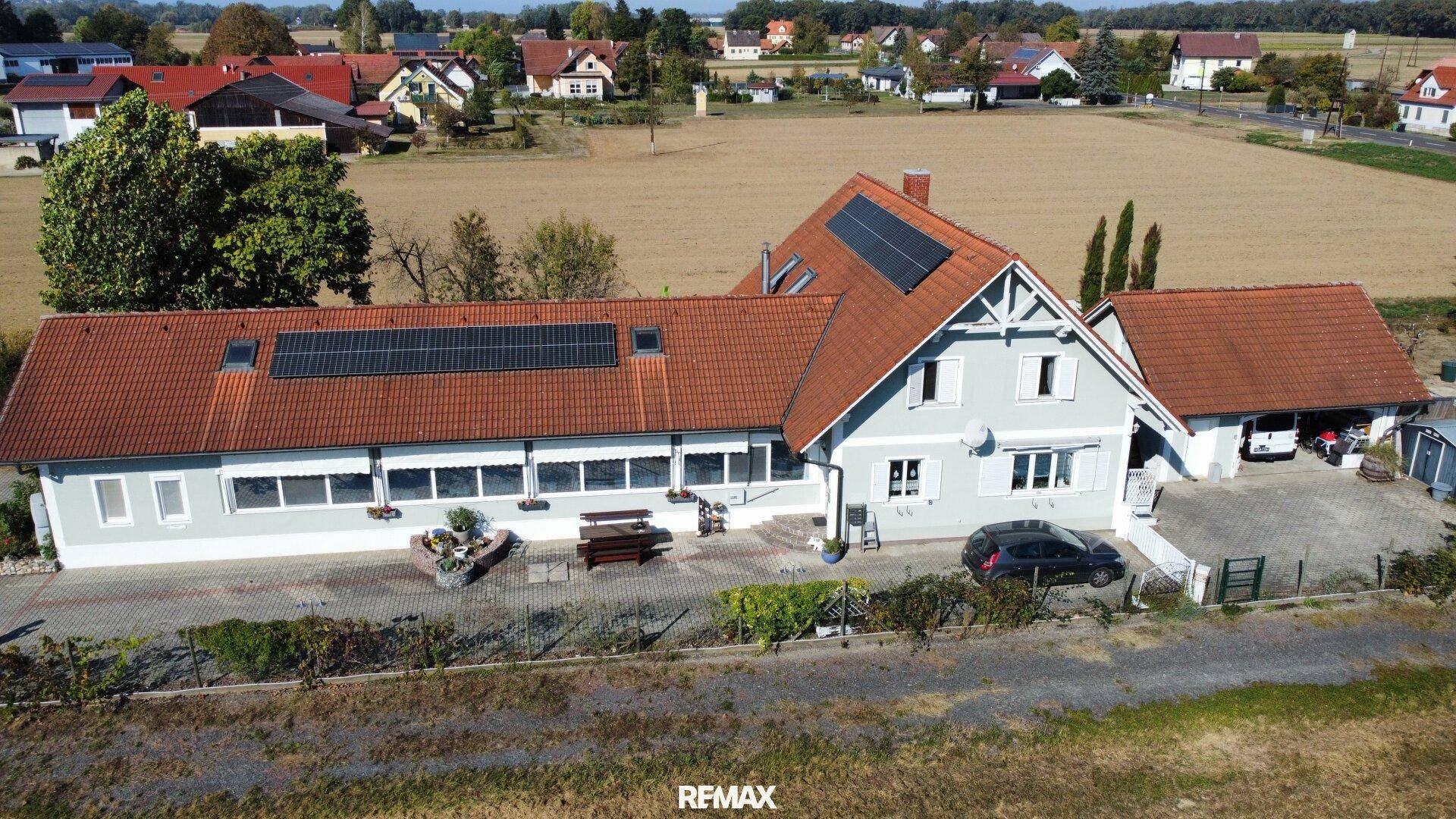 Gesamtansicht des Hauses aus der Luft mit Photovoltaik auf den Dächern und weitläufigem Grundstück.