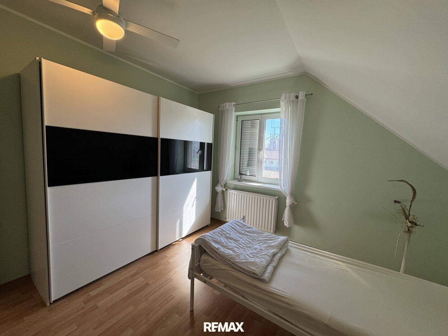 Schlafzimmer im Dachgeschoss mit großem Kleiderschrank, Einzelbett und Laminatboden.