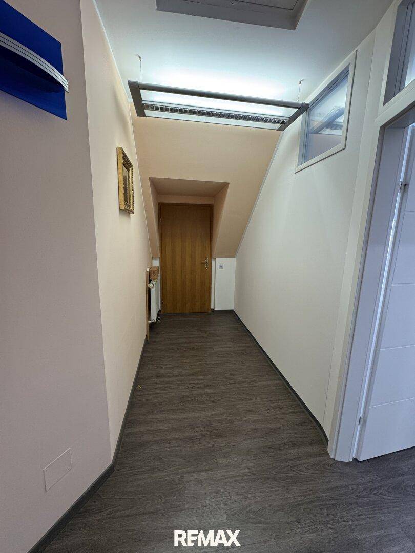 Heller Flur mit Laminatboden, Holztreppe und Zugang zu weiteren Räumen.