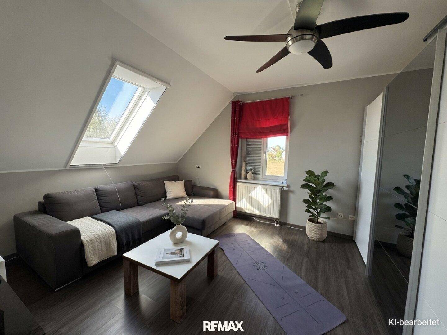 Modernes Wohnzimmer im Dachgeschoss mit Sofa, Couchtisch und Dachfenster.