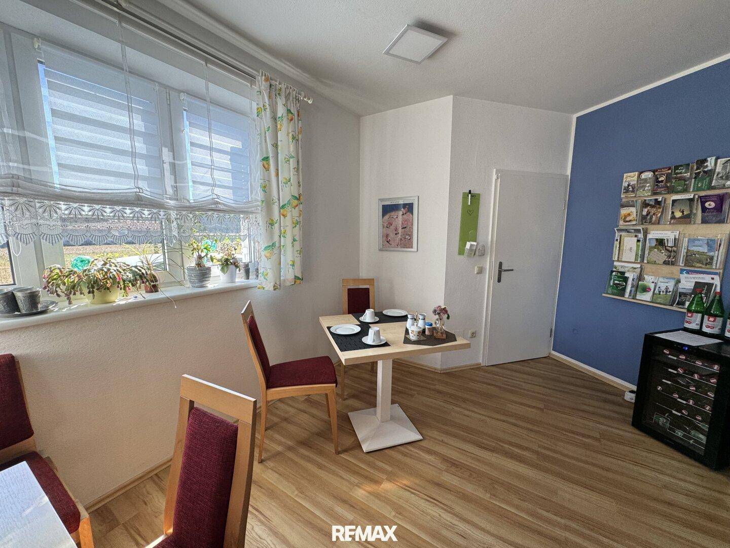 Gemütlicher Essbereich mit kleinem Tisch, Laminatboden und Fenster mit Jalousien.