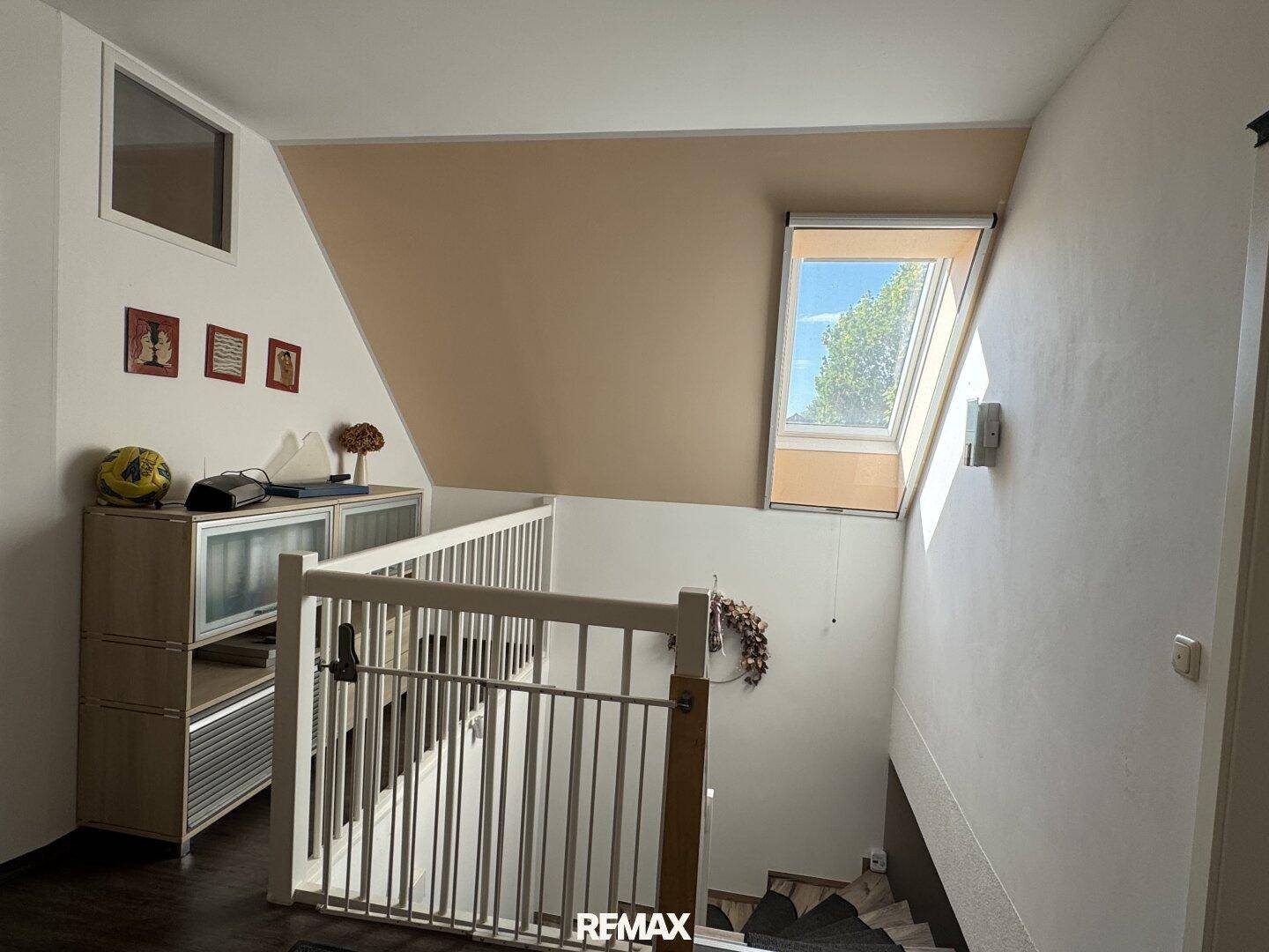 Treppenbereich mit Kinderschutzgitter, Dachfenster und schrägen Decken im Dachgeschoss.