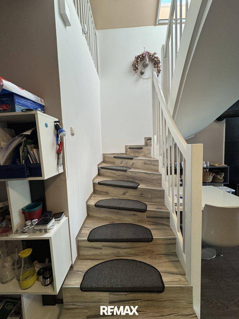 Treppenaufgang mit Holzstufen und weißem Geländer, der die Etagen verbindet.