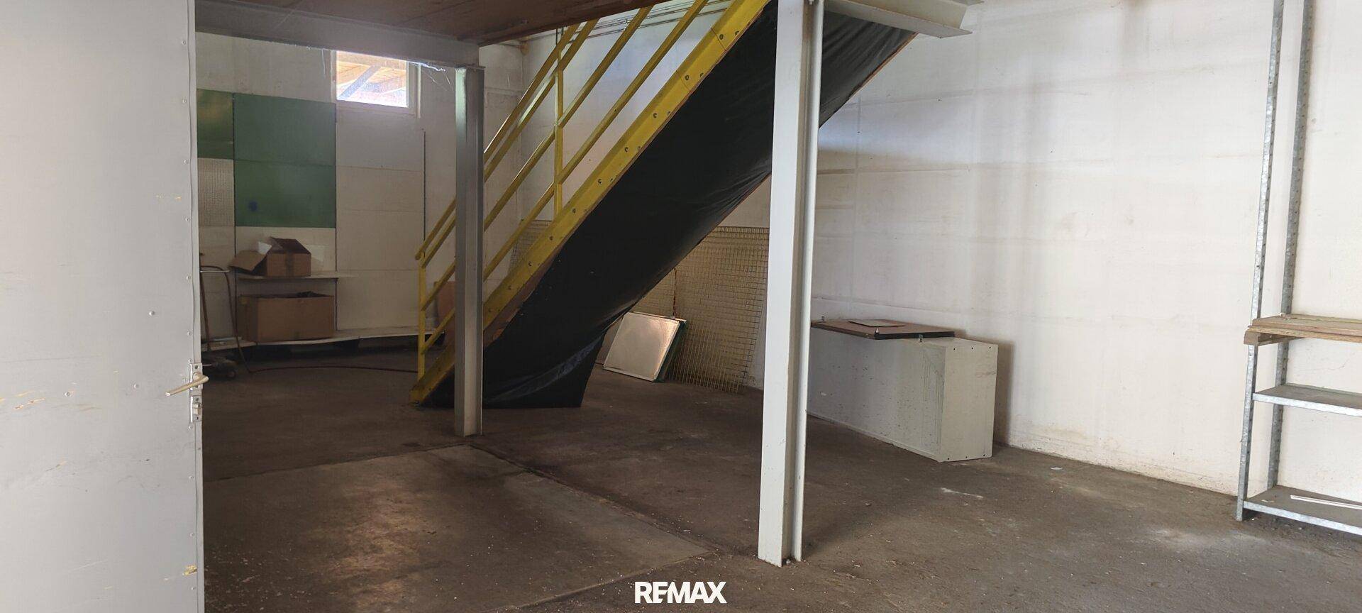 Lagerraum mit Betonsäulen und einer gelben Metalltreppe, bietet viel Stauraum.
