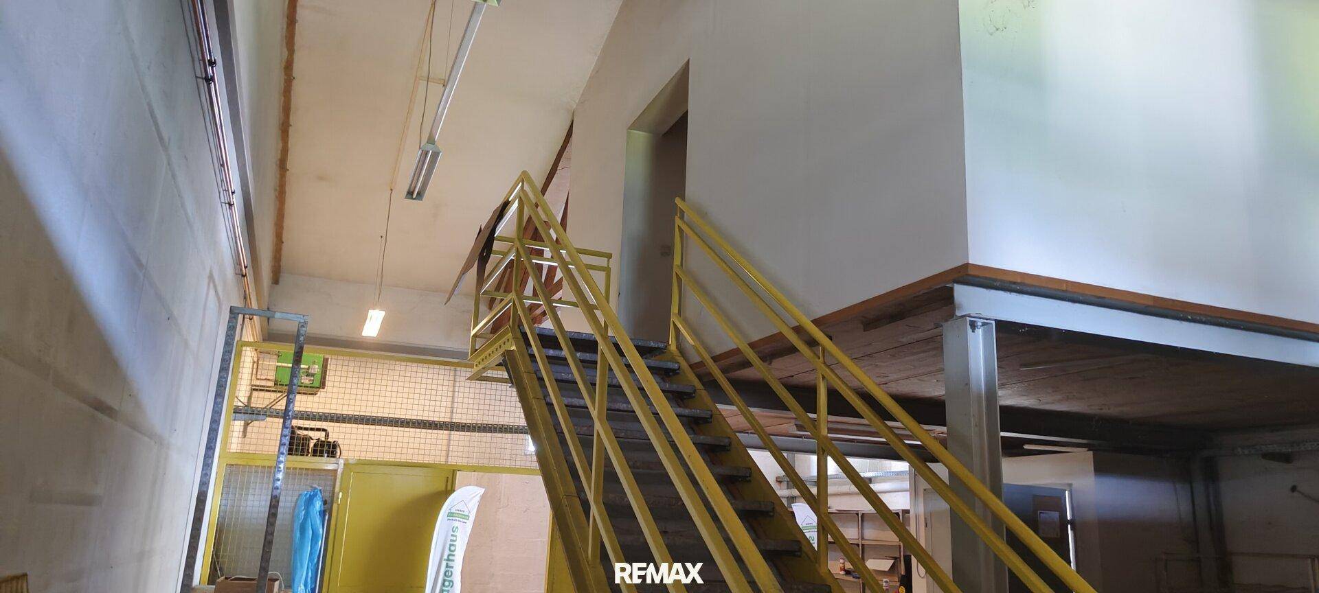Geräumiger Lagerbereich mit hoher Decke und gelber Metalltreppe, bietet viel Platz.