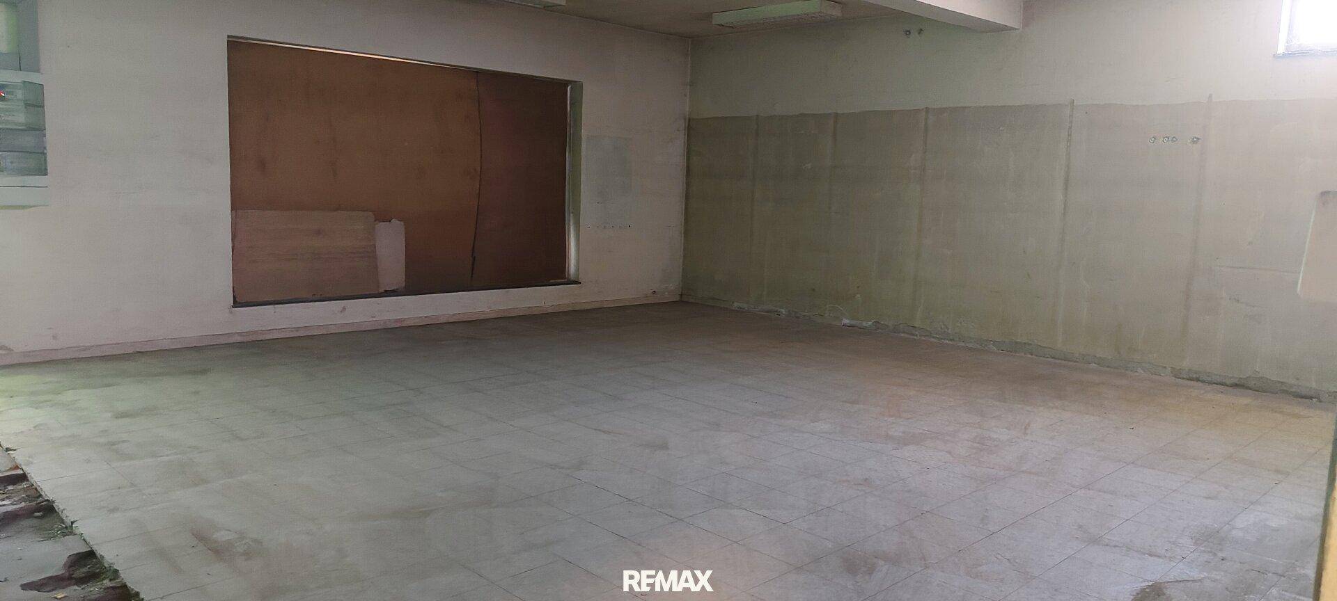 Leerer Raum mit Betonboden und einer zugemauerten Fensteröffnung, bereit zur Renovierung.
