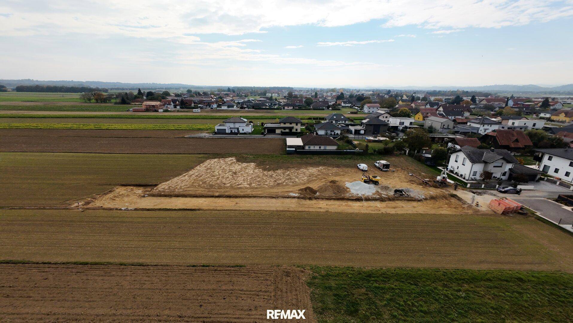 Luftaufnahme einer Baustelle mit Erdarbeiten für neue Baugrundstücke in ländlicher Umgebung.