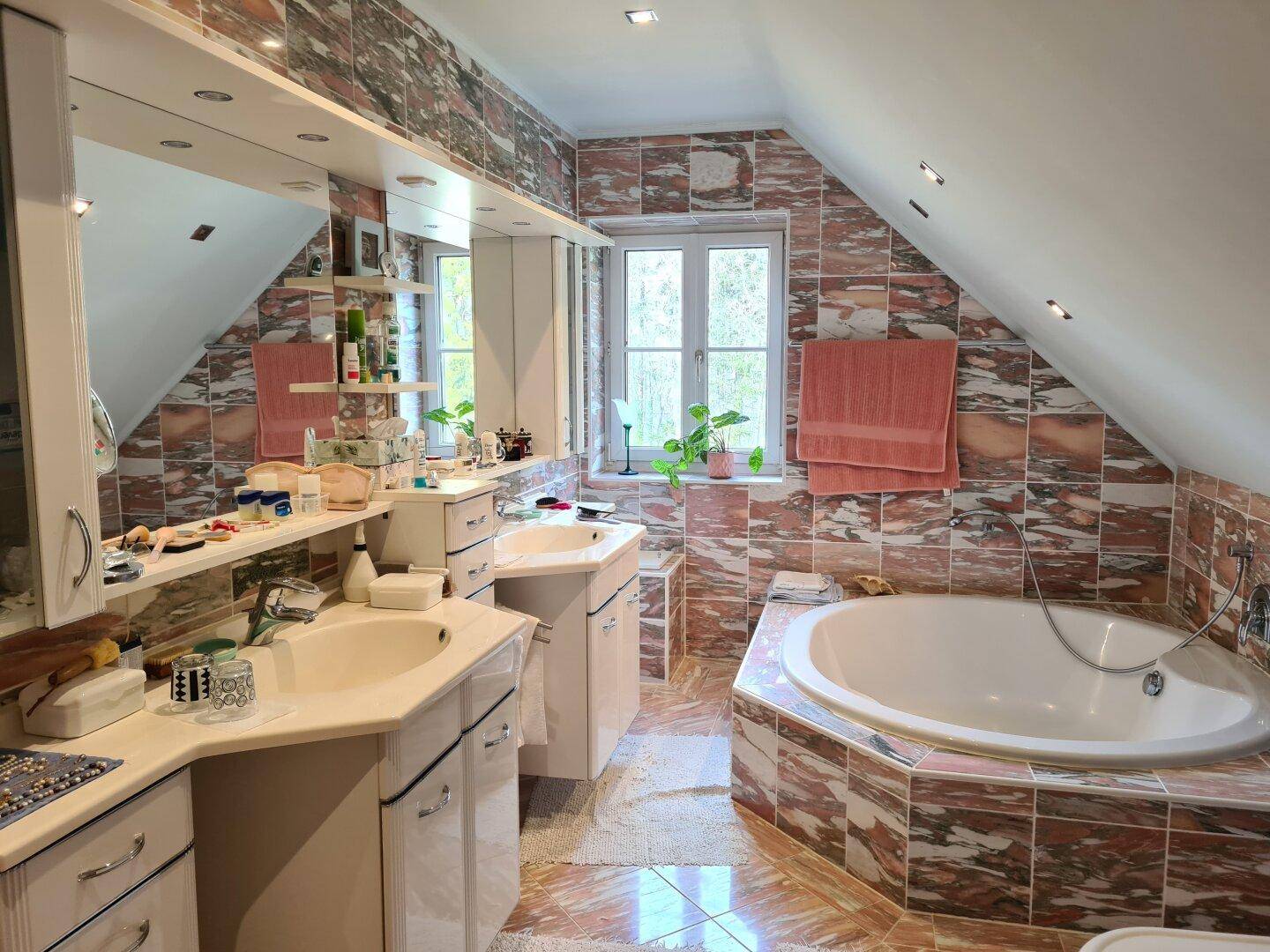 Geräumiges Badezimmer mit Eckbadewanne, Doppelwaschbecken und auffälligen Fliesen in Dachschräge.