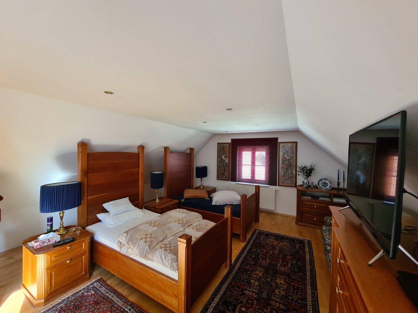 Gemütliches Schlafzimmer mit zwei Holzbetten, Parkettboden und Dachschräge.