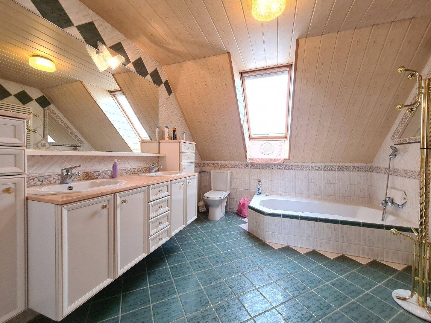 Helles Badezimmer im Dachgeschoss mit Badewanne, Toilette und Dachfenster.