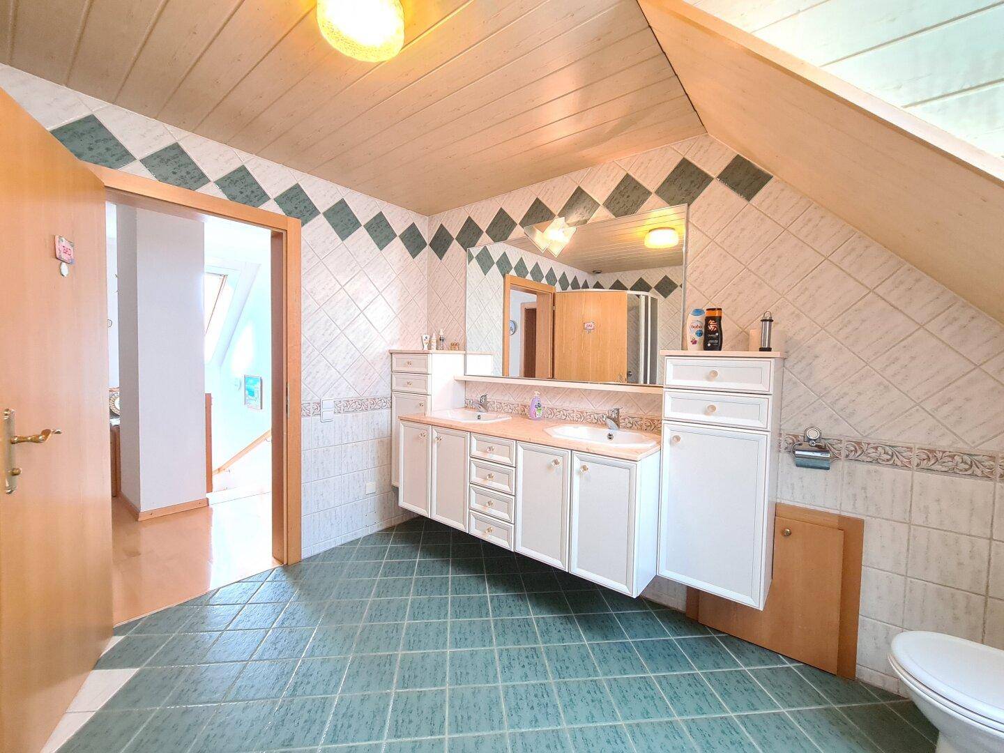 Geräumiges Badezimmer im Dachgeschoss mit Doppelwaschbecken, Badewanne und Dachfenster.