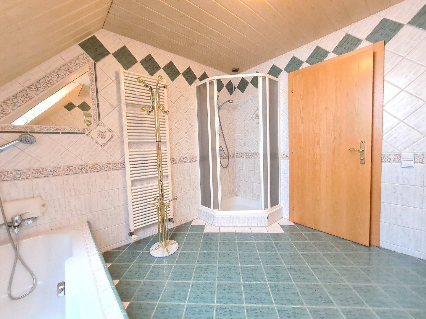 Badezimmer im Dachgeschoss mit Duschkabine, Badewanne und beheiztem Handtuchhalter.