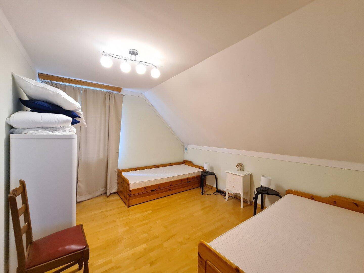 Geräumiges Schlafzimmer im Dachgeschoss mit zwei Betten und Parkettboden.