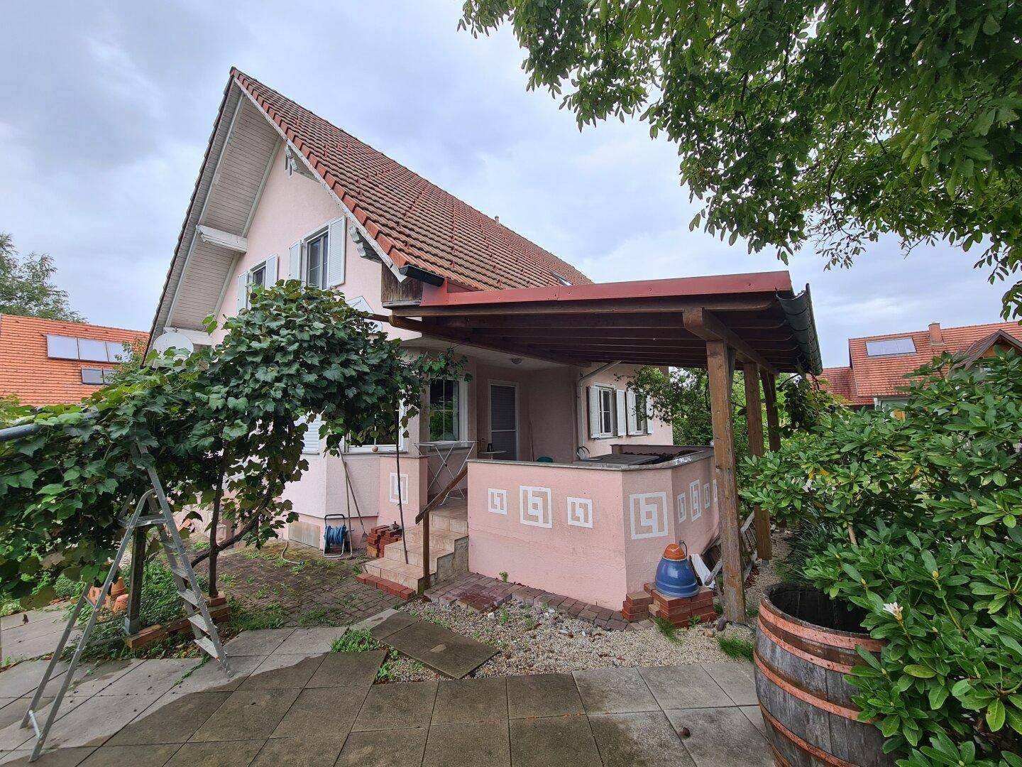 Überdachte Terrasse am Haus mit Zugang zum Garten und Blick ins Grüne.