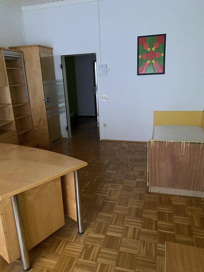 Geräumiges Zimmer mit Schreibtisch, Bett und Holzparkettboden, ideal für Arbeits- und Schlafbereich.