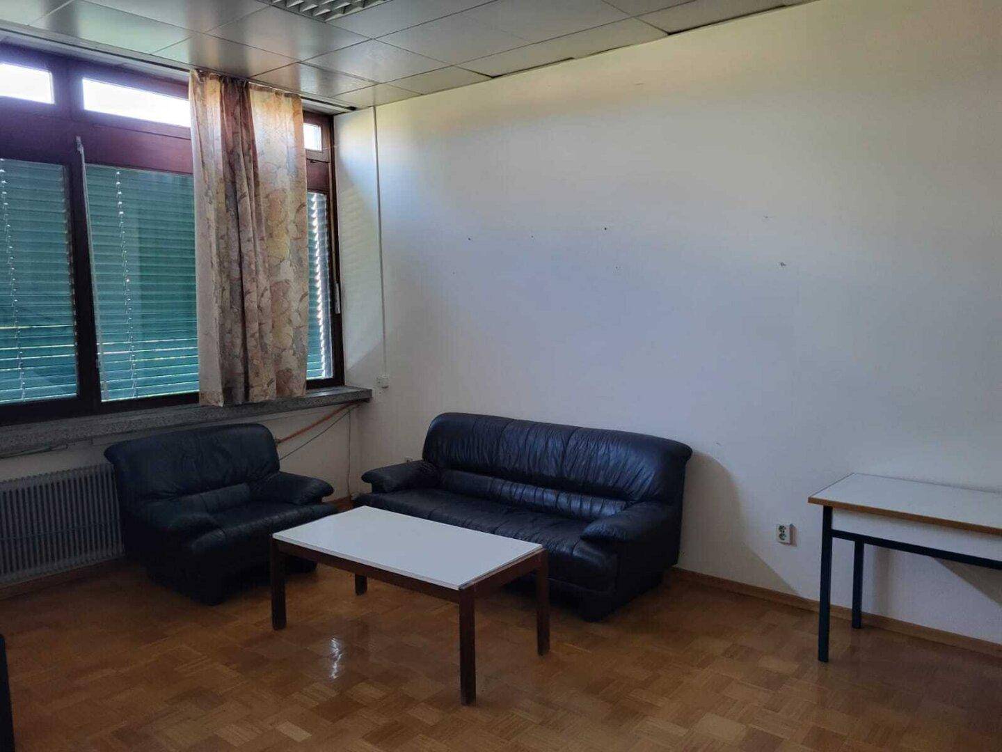 Gemütlicher Aufenthaltsbereich mit Ledersofas, Couchtisch und Holzparkettboden vor einem Fenster.