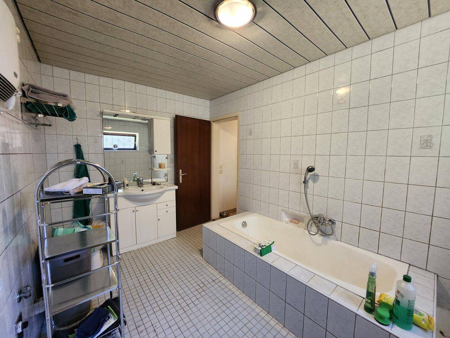 Gefliestes Badezimmer mit Badewanne, Waschbecken und Spiegelschrank.