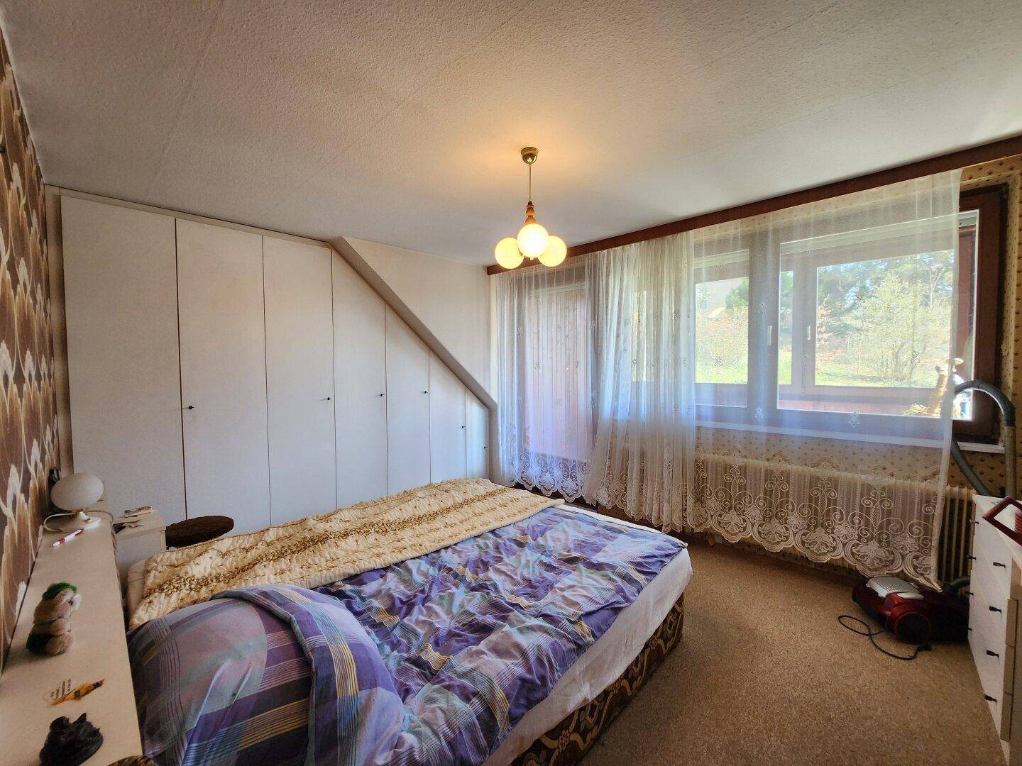 Gemütliches Schlafzimmer mit Einbauschränken, Teppichboden und einem großen Fenster.