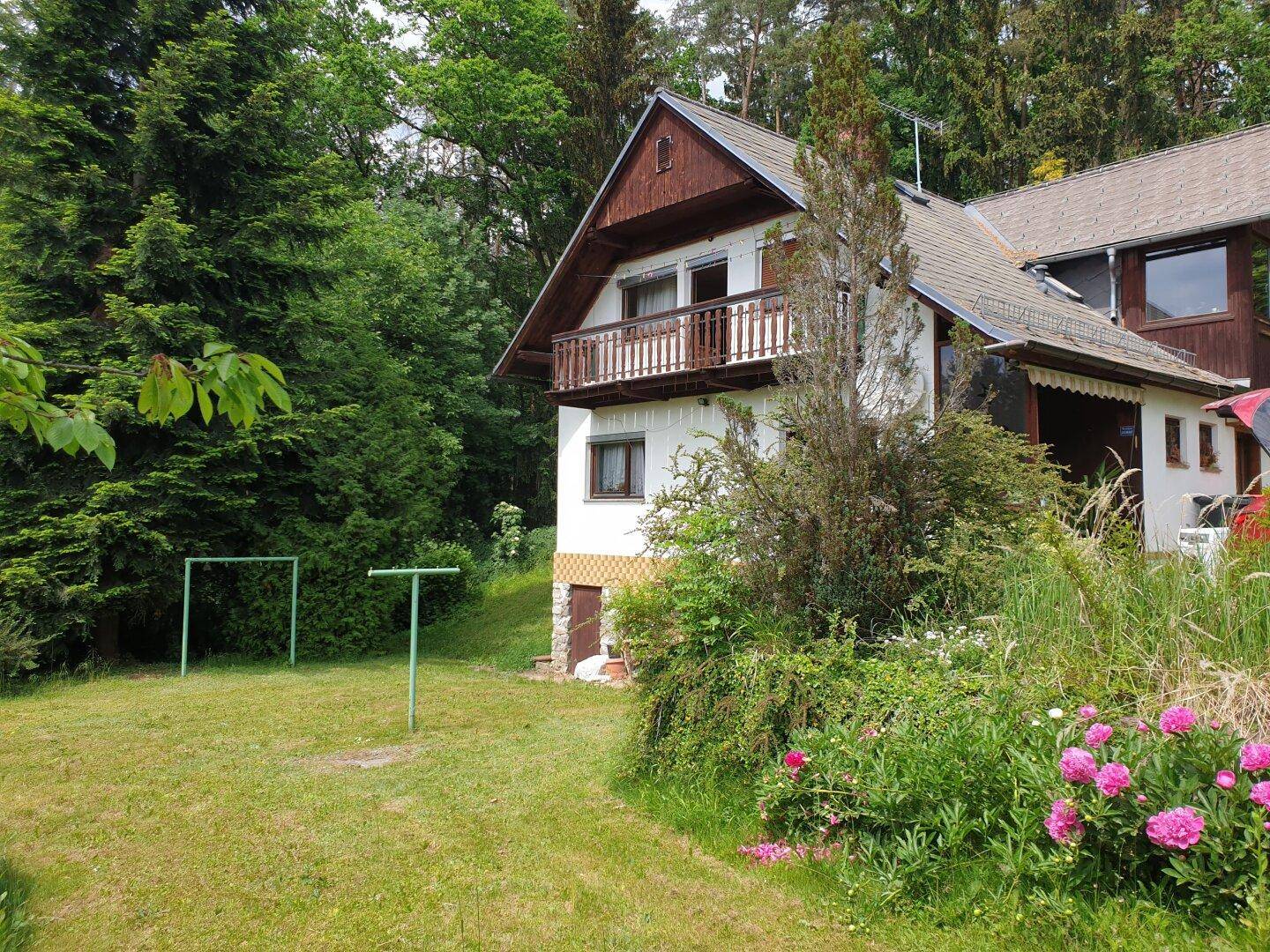Seitlicher Gartenbereich mit Wäscheleinen und blühenden Sträuchern neben dem Haus.