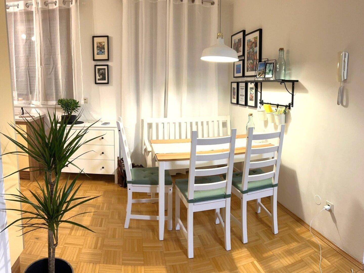 Heller Essbereich mit Holztisch, weißen Stühlen und Parkettboden, ideal für Familienmahlzeiten.