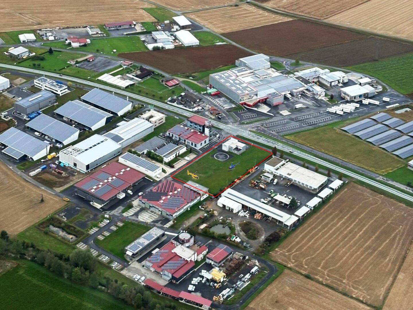 Weitläufige Luftaufnahme eines Industrie- und Gewerbekomplexes mit vielen Gebäuden und umliegenden Feldern.