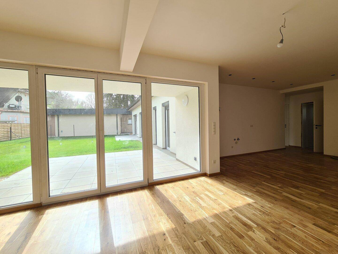 Geräumiger Wohnbereich mit Holzboden und Zugang zur Terrasse, lichtdurchflutet.