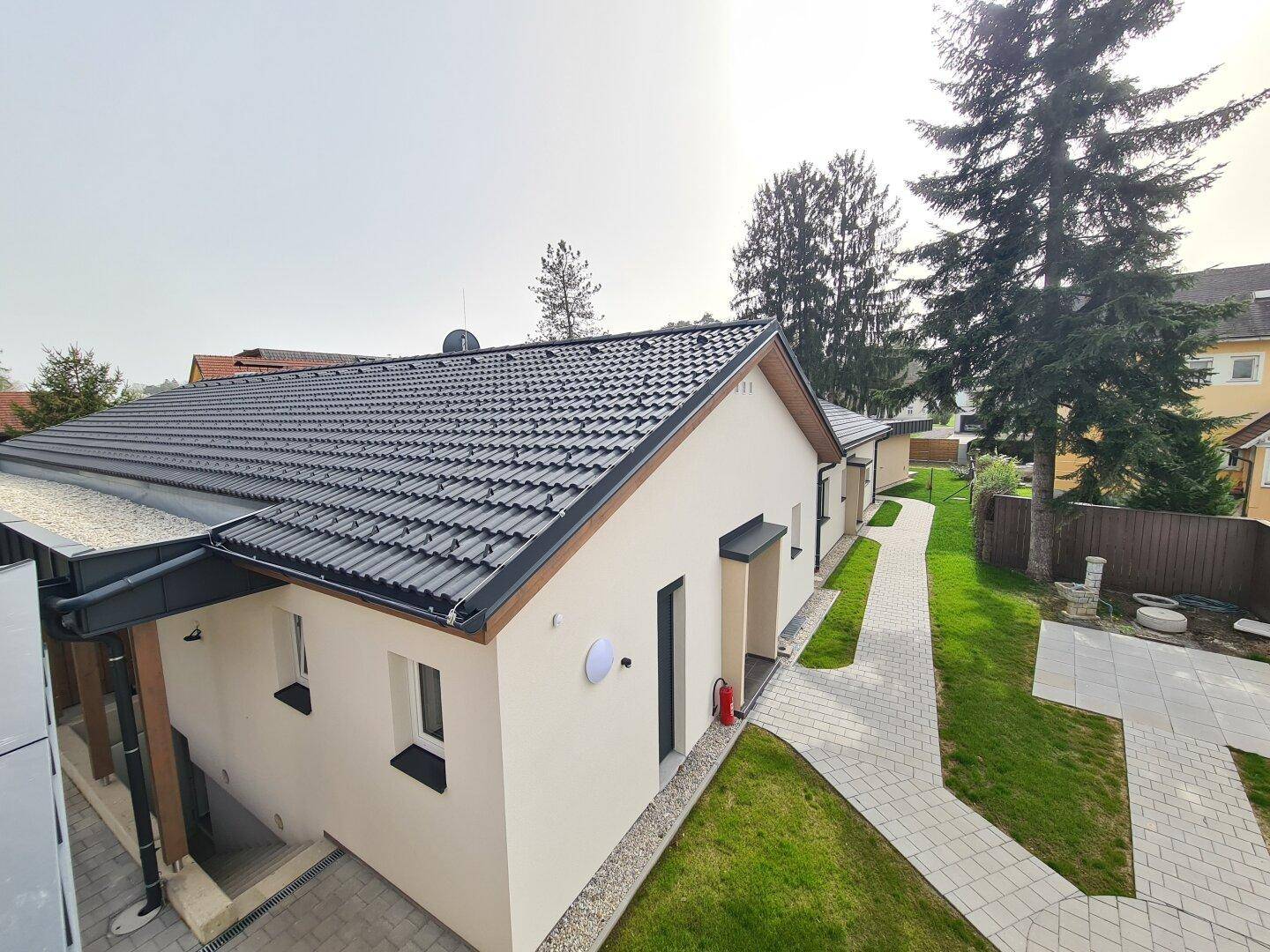 Ansicht des Neubaus von oben mit dunklem Ziegeldach und gepflegter Außenanlage.