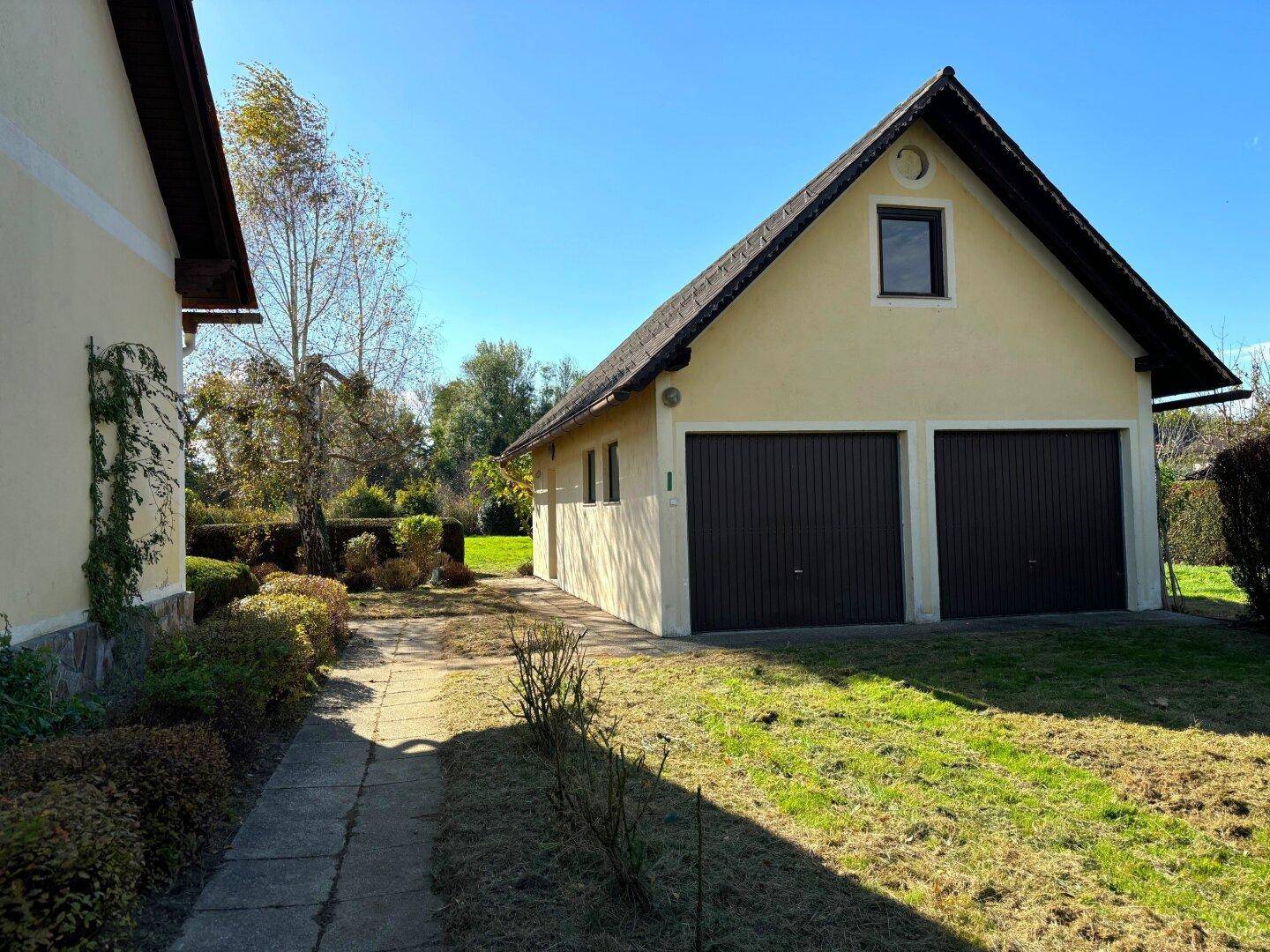 Freistehende Doppelgarage mit Satteldach und zwei braunen Toren neben dem Haupthaus.