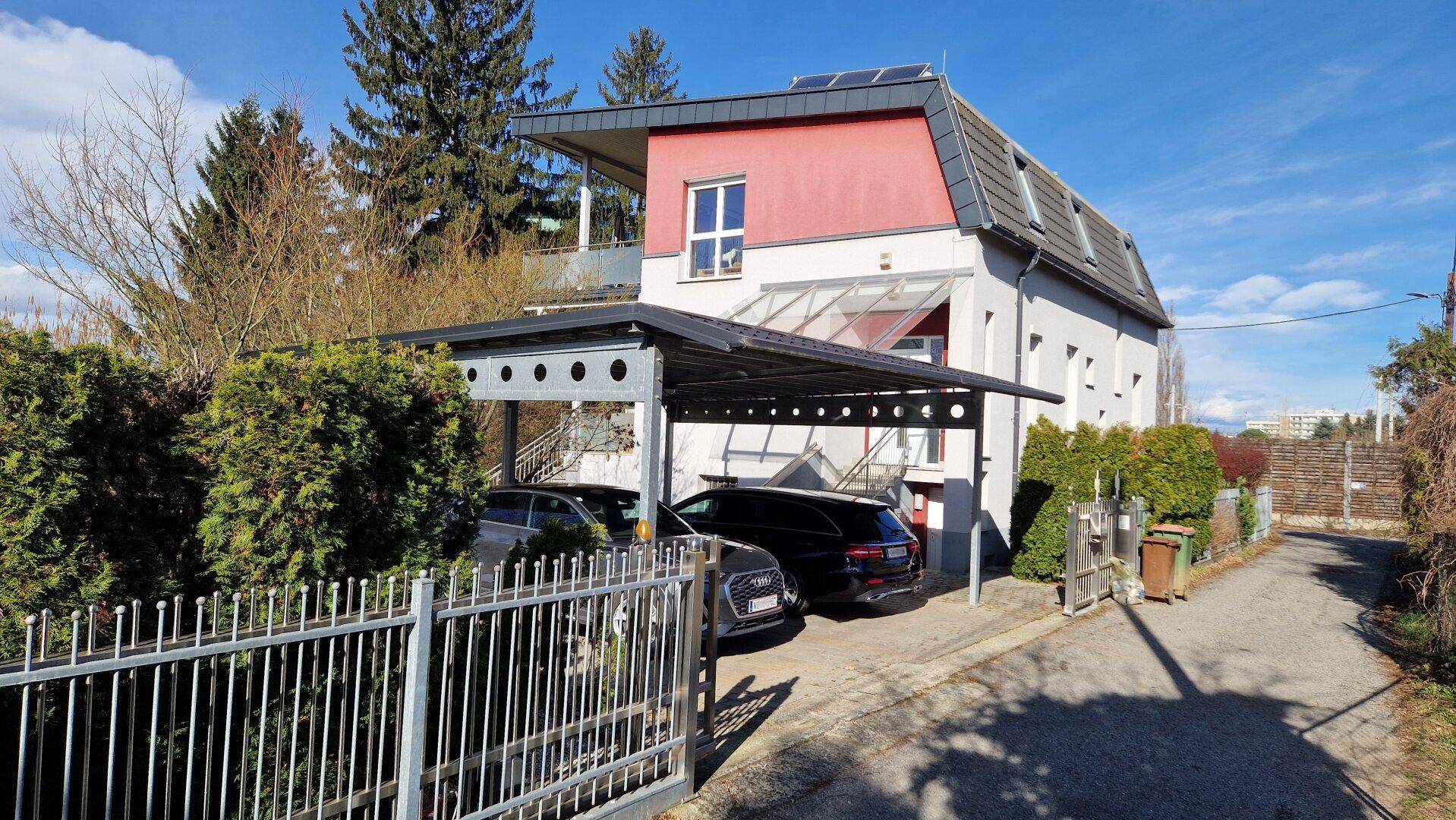 Vorderansicht des Hauses mit Carport für zwei Fahrzeuge und Solarpaneelen auf dem Dach.