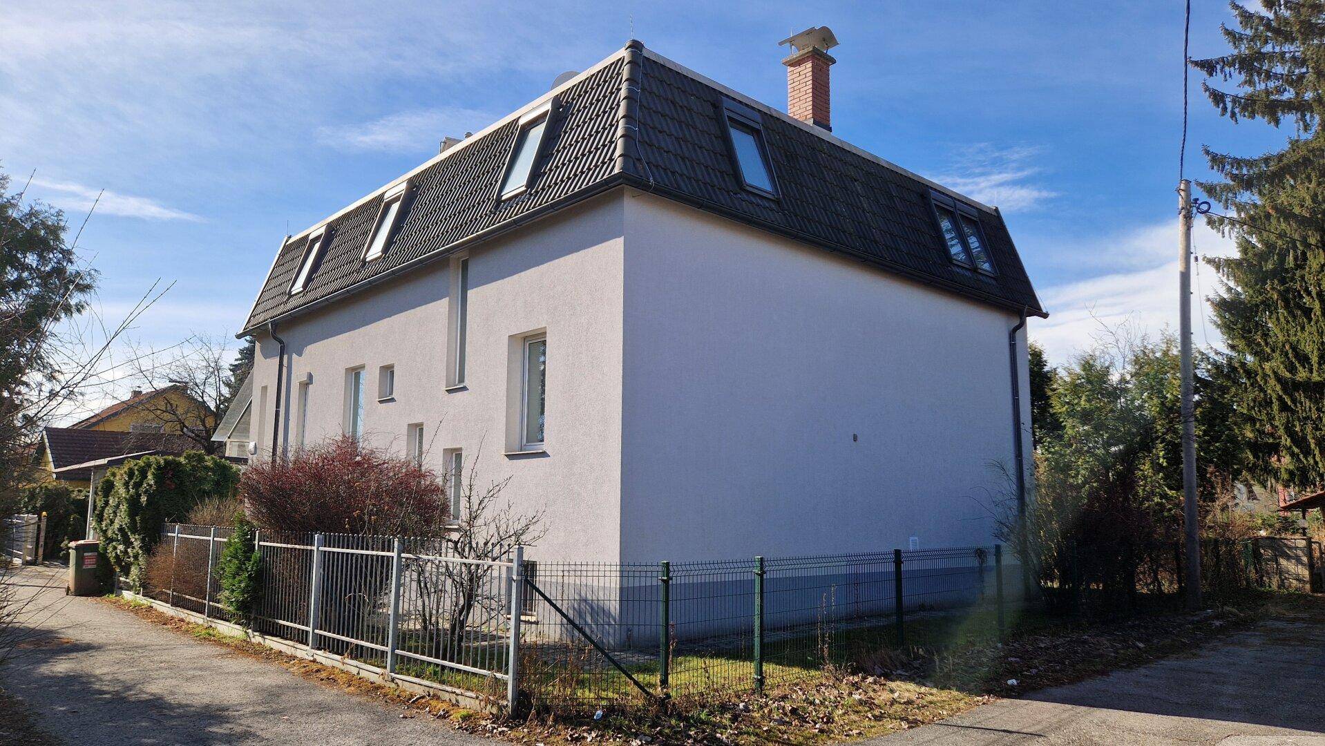 Seitenansicht des Hauses mit Mansarddach und mehreren Dachfenstern.