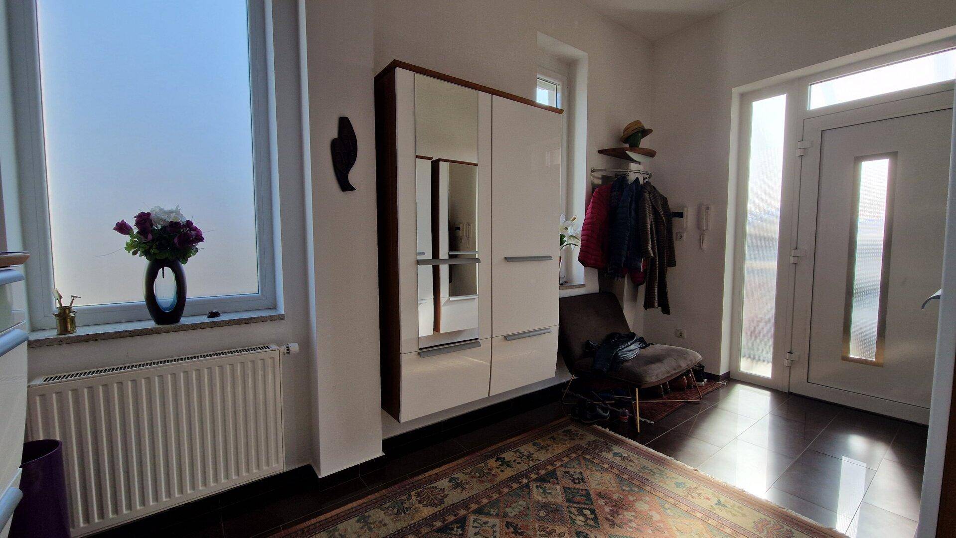 Eingangsbereich mit Garderobe, Fenster und dunklem Parkettboden.