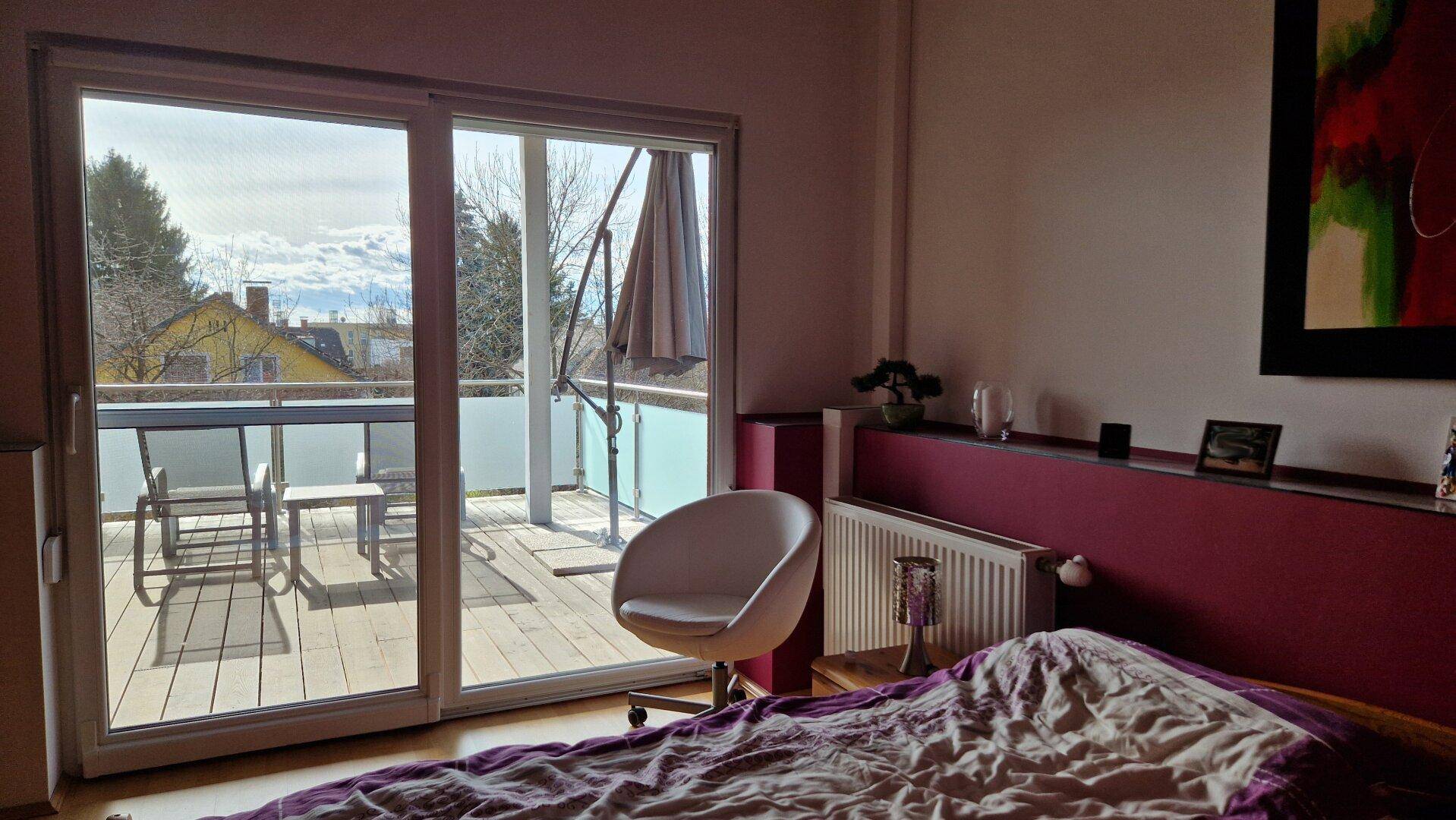 Schlafzimmer mit Balkonzugang, Doppelbett und Blick ins Grüne.