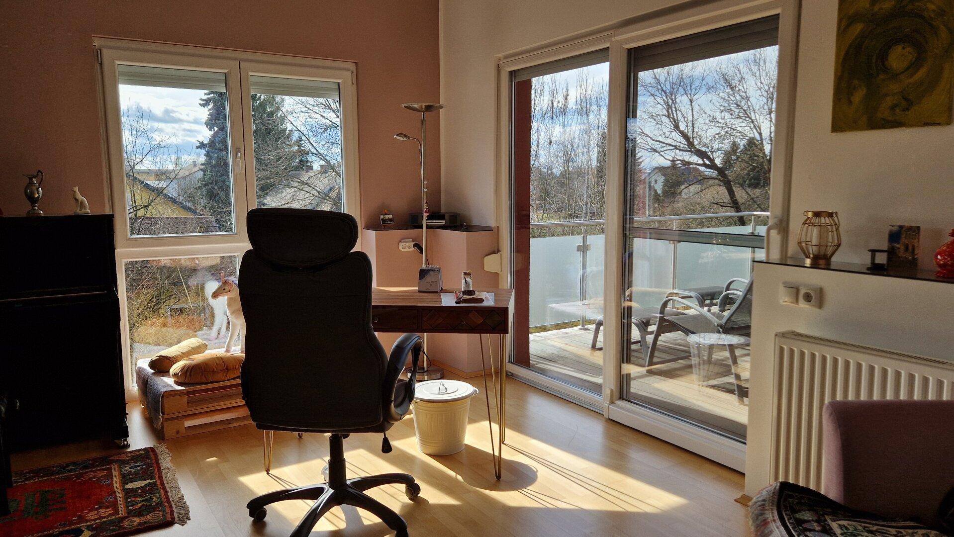 Helles Arbeitszimmer mit Schreibtisch, Holzboden und Zugang zum Balkon.