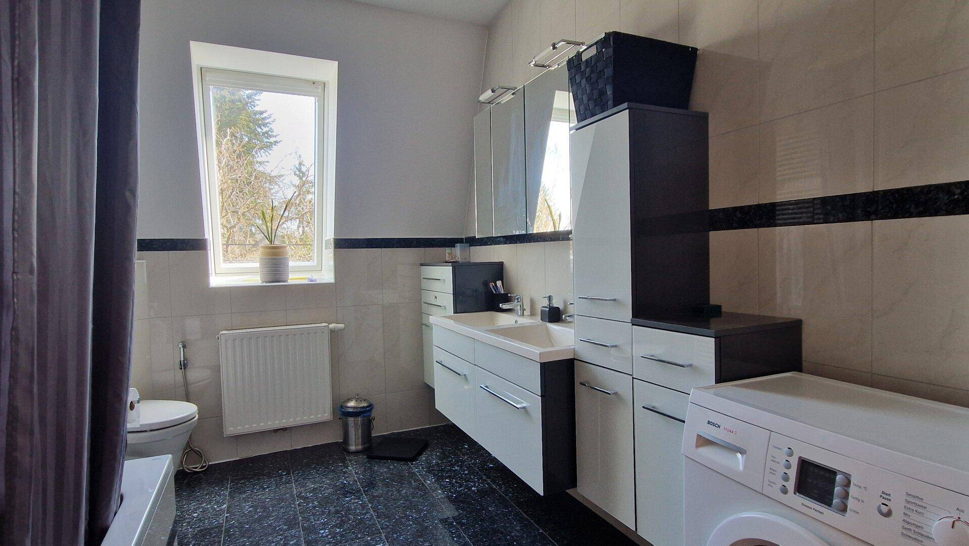 Badezimmer mit Badewanne, Waschbecken und Waschmaschine.