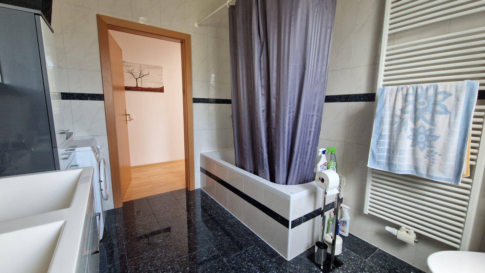 Badezimmer mit Badewanne, Duschvorhang und beheiztem Handtuchhalter.