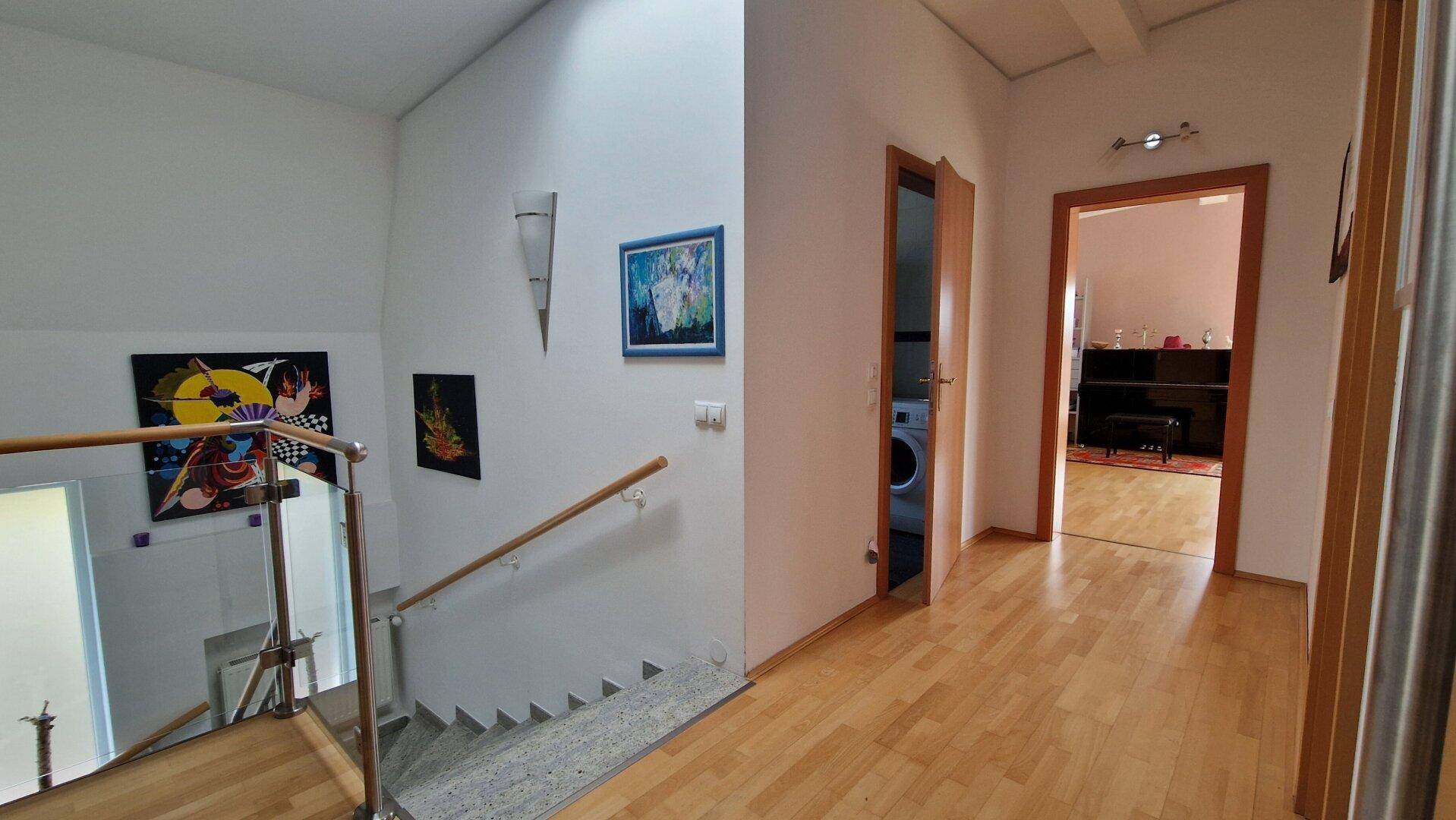 Heller Flur im Obergeschoss mit Holzparkett und Zugang zu weiteren Räumen.