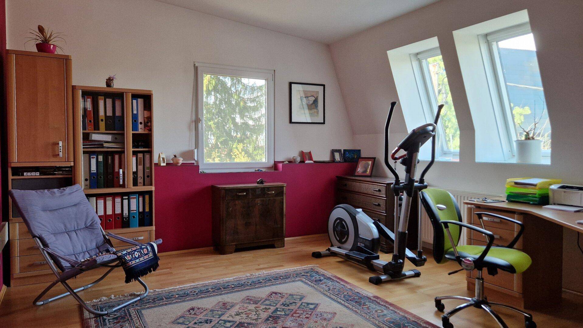 Geräumiges Arbeitszimmer mit Fitnessgerät, Schreibtisch und Dachfenstern.