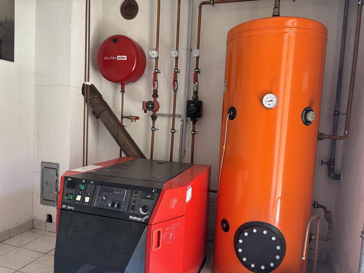 Heizungsraum mit großem Warmwasserspeicher und Heizkessel für die Wärmeversorgung.
