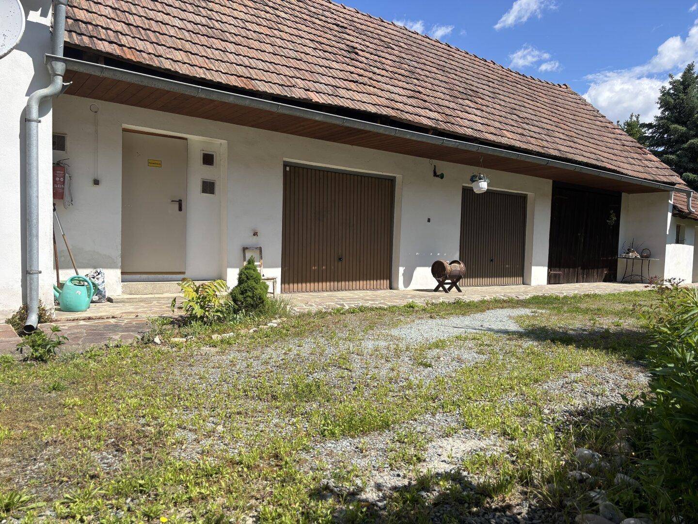 Rückseite des Hauses mit zwei Garagentoren und einem gepflegten Kiesbereich davor.